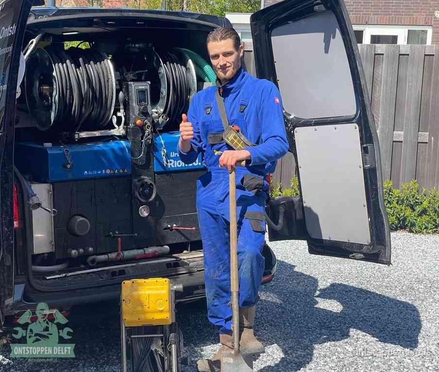 Een tevreden monteur met opgestoken duim naast de bestelbus, slim ingrijpen bespaart kosten bij een verstopte afvoer in Delft