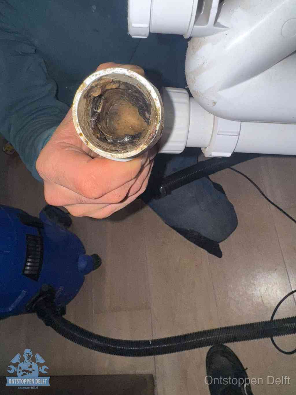 Een losgekoppeld afvoerbuisstuk dat van binnen volledig is dichtgeslibd, het gevolg van een verstopping te lang laten zitten in Delft