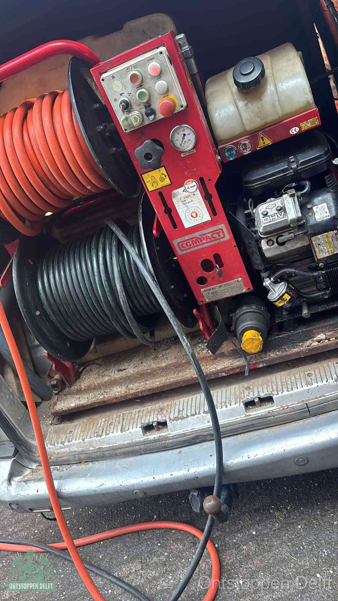 Een rood hogedruk-rioolreinigingstoestel in de laadbak van de bedrijfsbus, apparatuur voor een hardnekkige afvoerverstopping in Delft