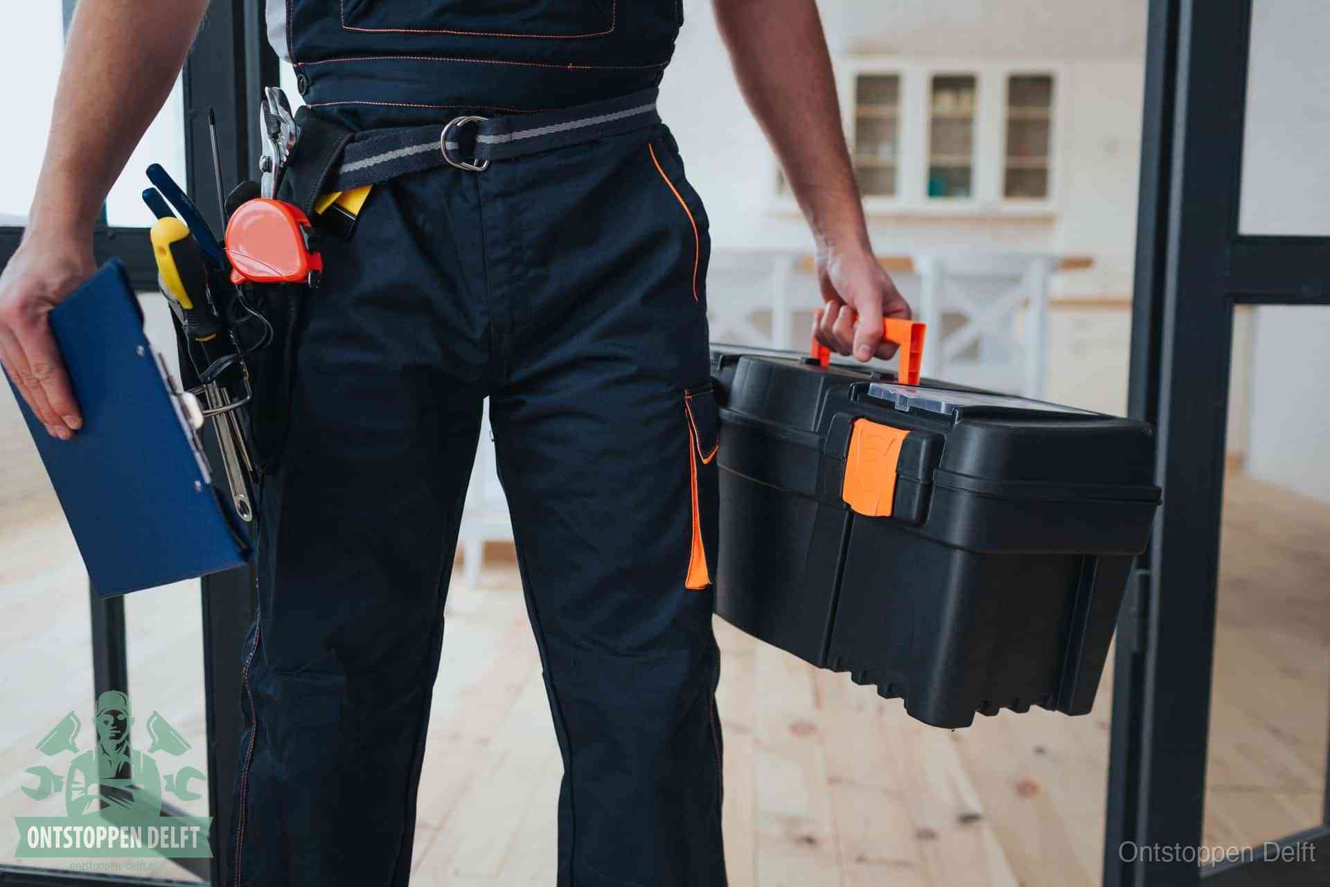 Een monteur met gereedschapsriem en klembord, klaar om een transparante prijs voor het afvoer ontstoppen in Delft te geven