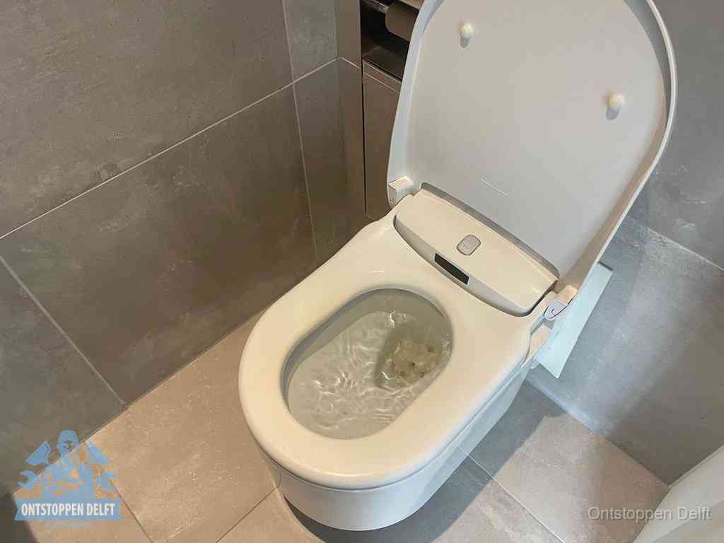Een toiletpot vol troebel water met drijvend papier en restanten, de meest voorkomende oorzaak van een verstopte wc in Delft