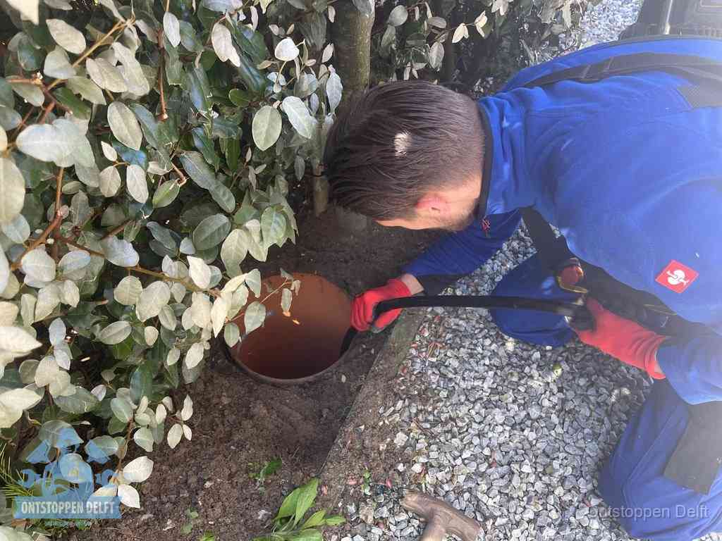 Monteur reinigt een rioolput met een slang, periodieke rioolreiniging in Delft