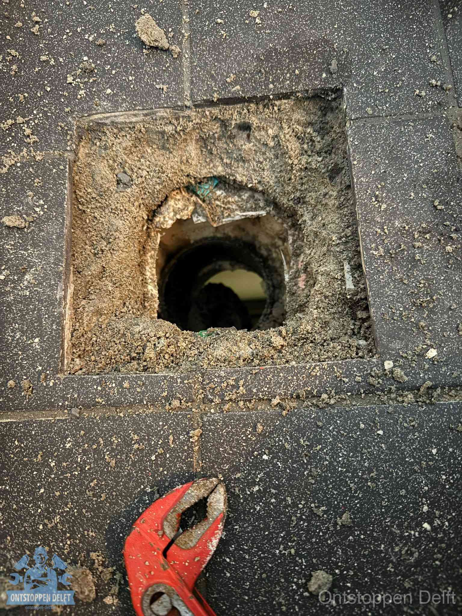 Geopend rioolputje op de erfgrens dat laat zien wie eigenaar is van de riolering in Delft