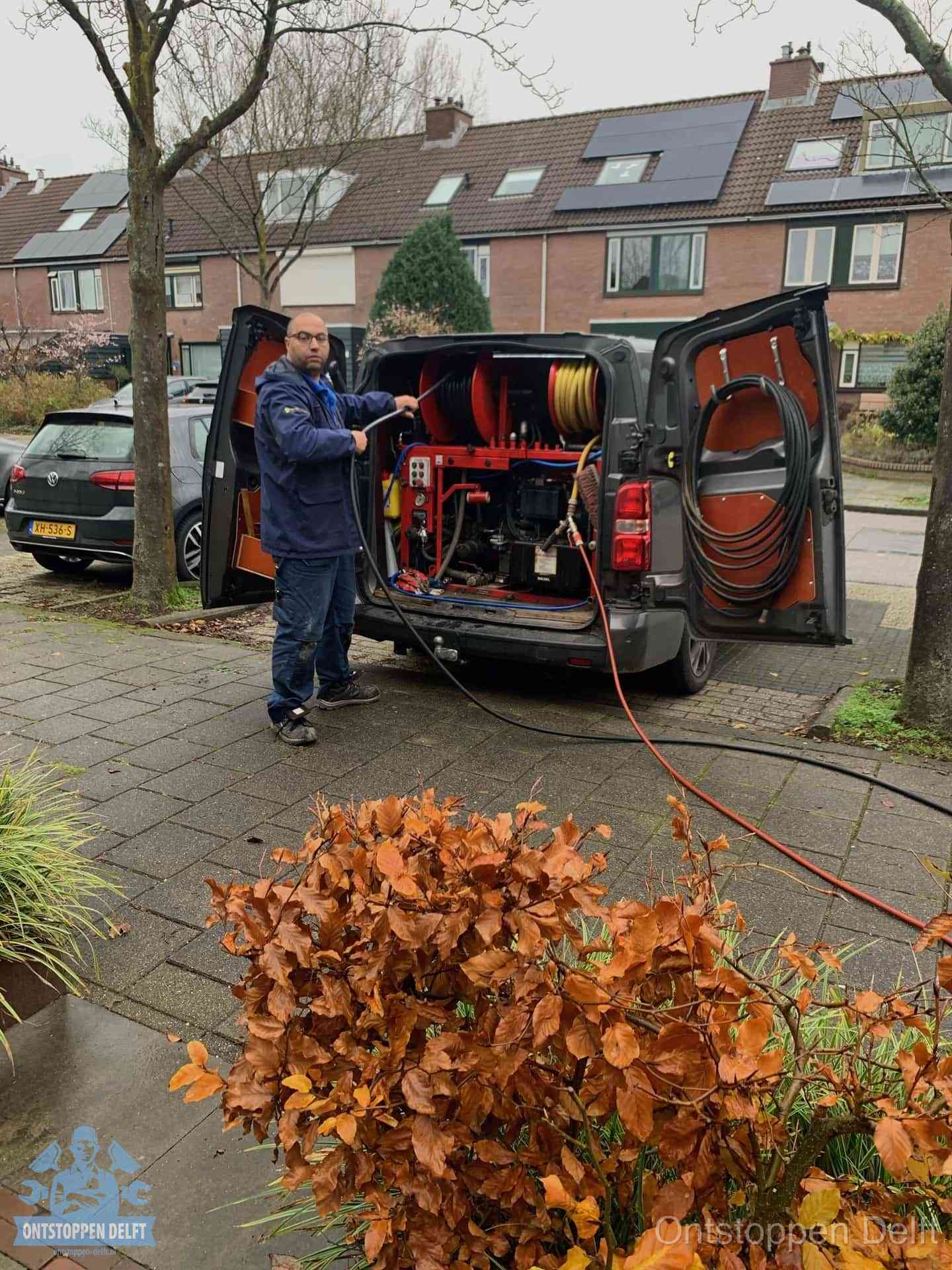 Monteur met rioolreinigingsbus levert rioolservice in de wijk in Delft