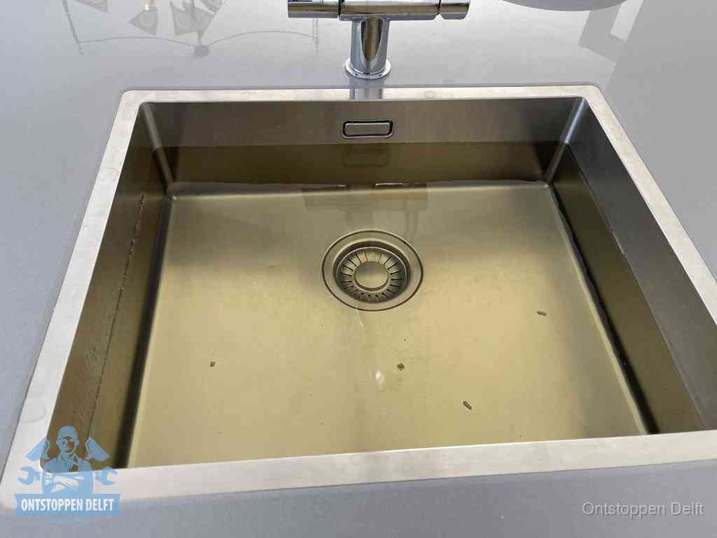 Stilstaand water in een rvs spoelbak dat niet wegloopt, een duidelijk signaal van een gootsteenverstopping in Delft