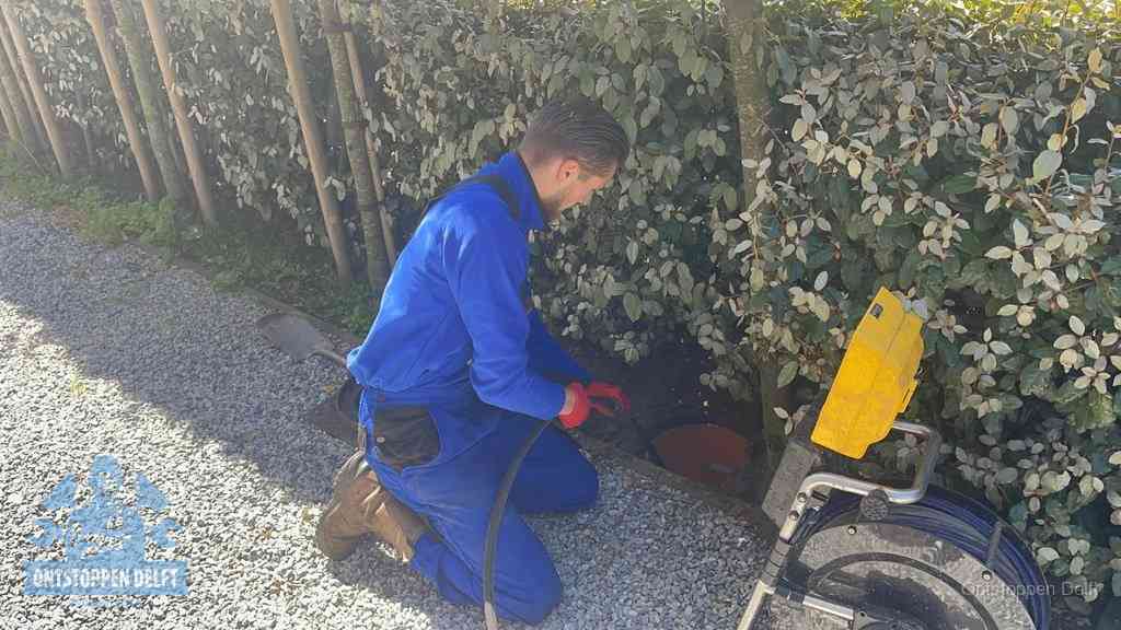 Monteur aan het werk bij een rioolput, de werkwijze voor riool ontstoppen in Delft