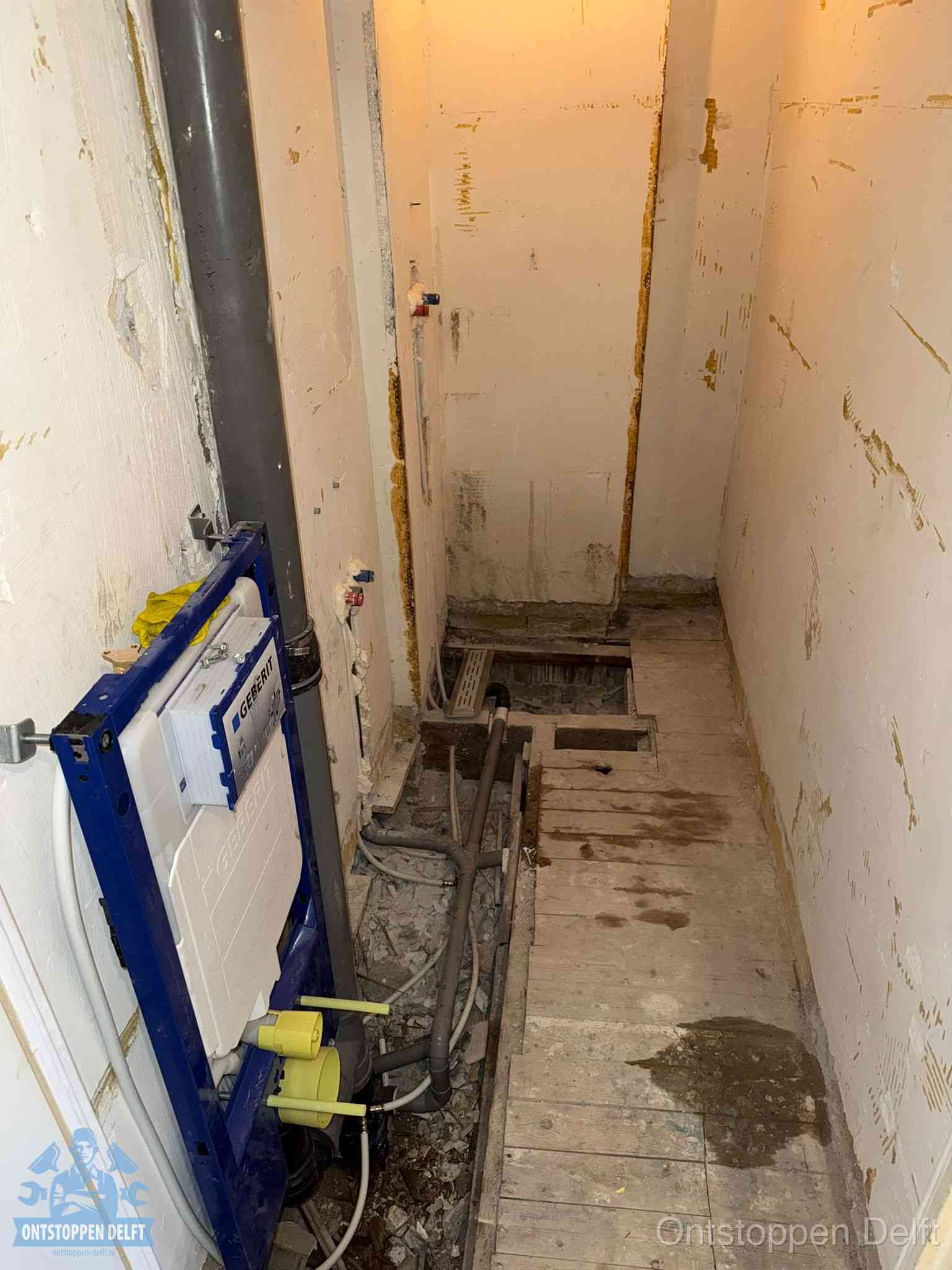 Een opgebroken toiletruimte tijdens renovatie met een Geberit inbouwreservoir en blootliggende oude afvoerleidingen, typisch voor oudere woningen in Delft