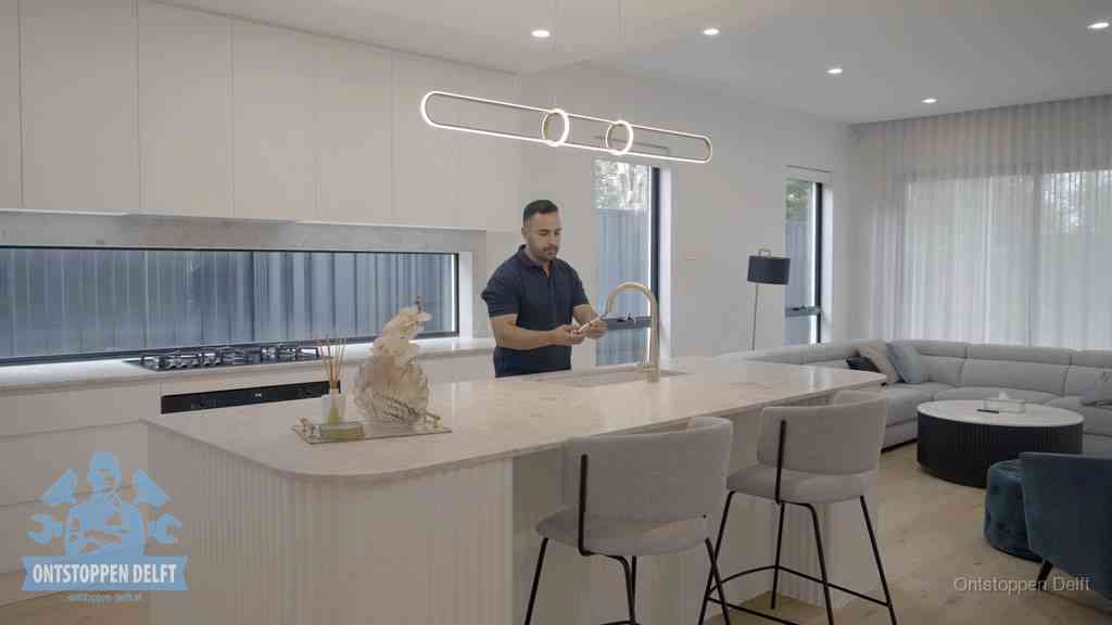 Een bewoner bij de keukenspoelbak die zelf aan de slag gaat met een verstopte gootsteen in Delft